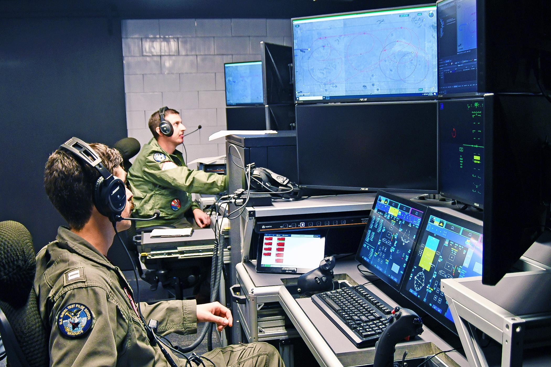 MQ-25 Air Vehicle Pilots Lt. Matt Pence (forward) and Lt. Steven Wilster conduct a test run to monitor the Unmanned Carrier Aviation Mission Control System ground control station, located at Naval Air Station Patuxent River, Md., as the system commands the General Atomics Aeronautical Systems, Inc. (GA-ASI) MQ-20 Avenger surrogate, located at the company’s test facility in California, in preparation for demonstration event in November 2024. (Photo: U.S. Navy)